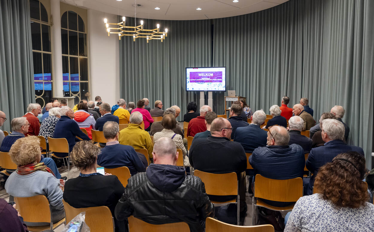 Een groep mensen woont een participatie bijeenkomst bij.