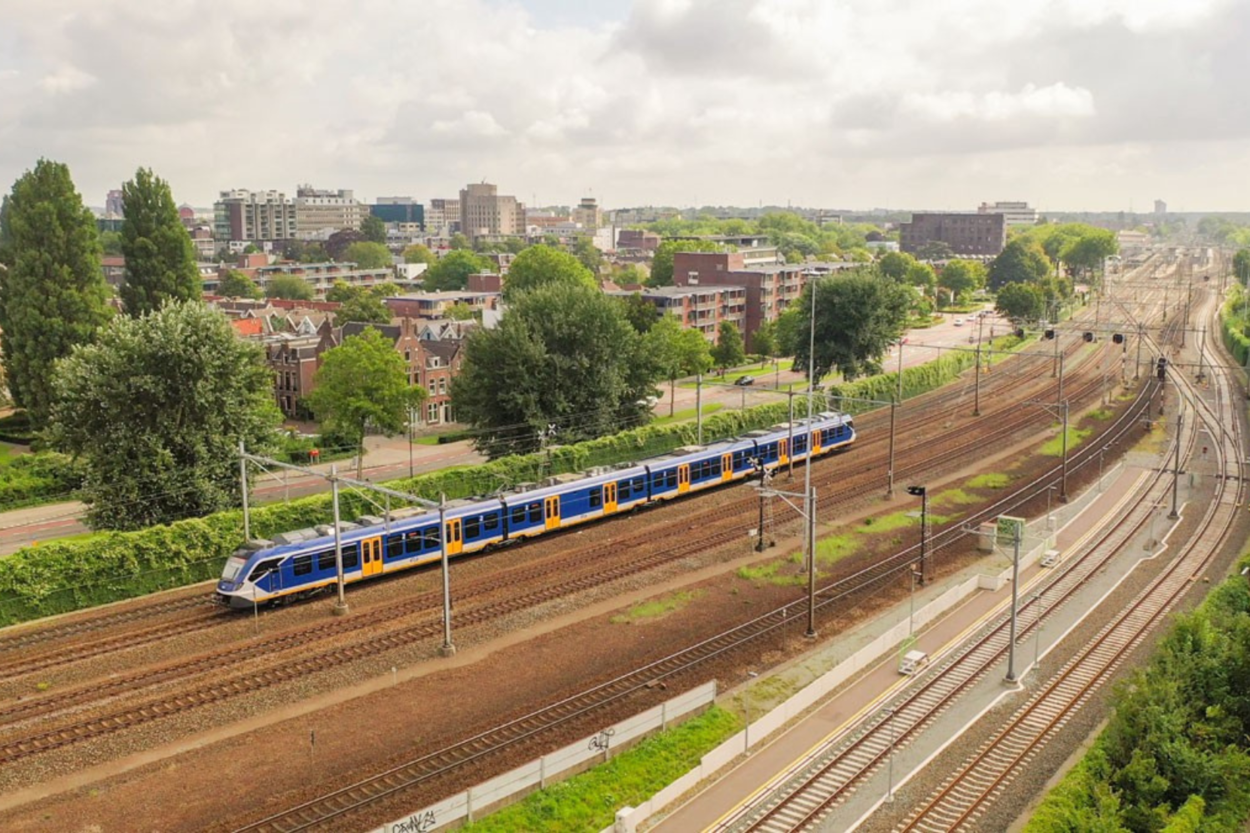 Een foto genomen van een hoog uitkijkpunt. Je ziet van links naar rechts het spoor met daarop een trein rijden.